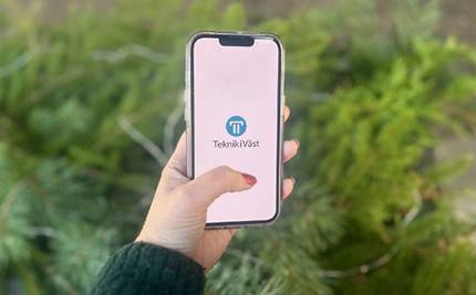 Hand som håller telefon med Teknik i Västs app mot grönskande bakgrund