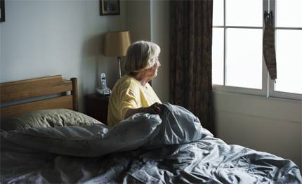 Kvinna som sitter på sängkanten